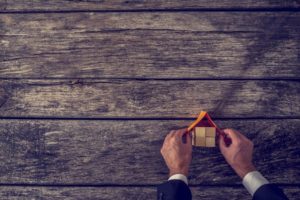 Man is holding a paper roof on a pretend home